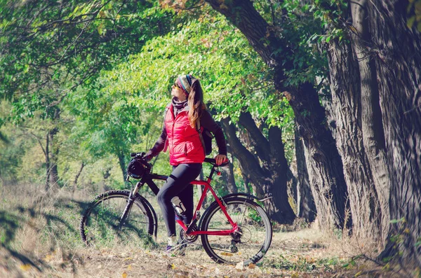 Menina com uma bicicleta entre as árvores — Fotografia de Stock