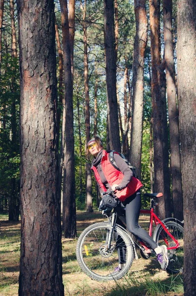 Menina com uma bicicleta entre as árvores — Fotografia de Stock