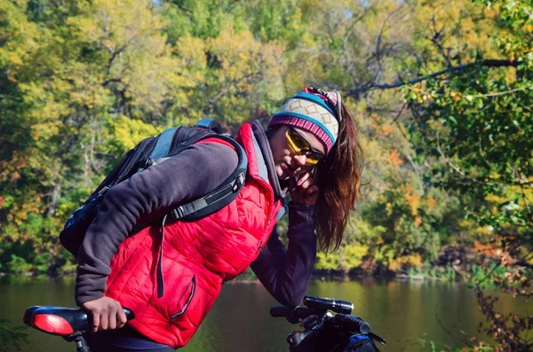 Menina com uma bicicleta entre as árvores — Fotografia de Stock