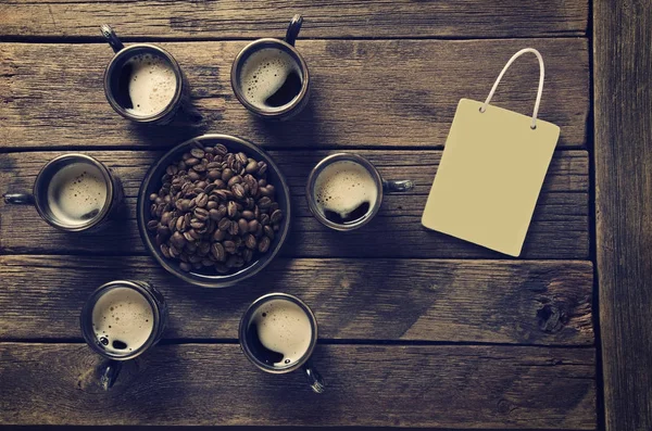 Tazas con café caliente y granos en la superficie del tablero — Foto de Stock