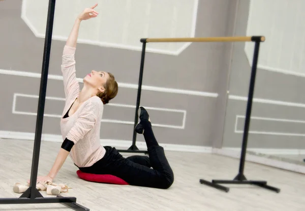 Довольно молодая изящная балетная танцовщица согревается в балетном классе — стоковое фото