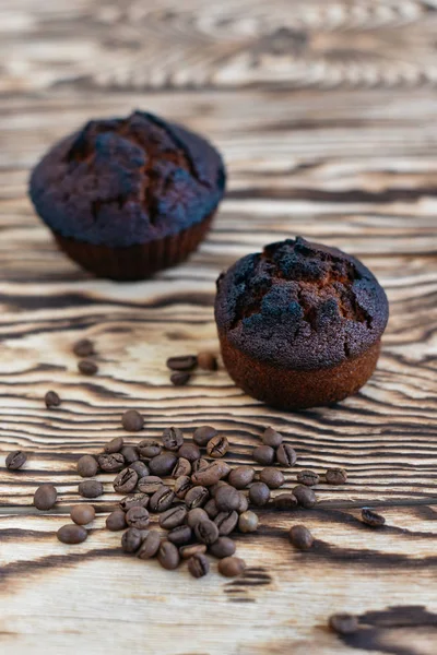 Φρέσκα νόστιμα cupcake και αρωματικά κόκκοι του καφέ σε φόντο ξύλινη — Φωτογραφία Αρχείου