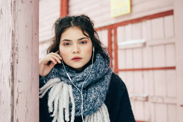 Una linda chica se sienta y escucha música en la temporada de invierno —  Fotos de Stock
