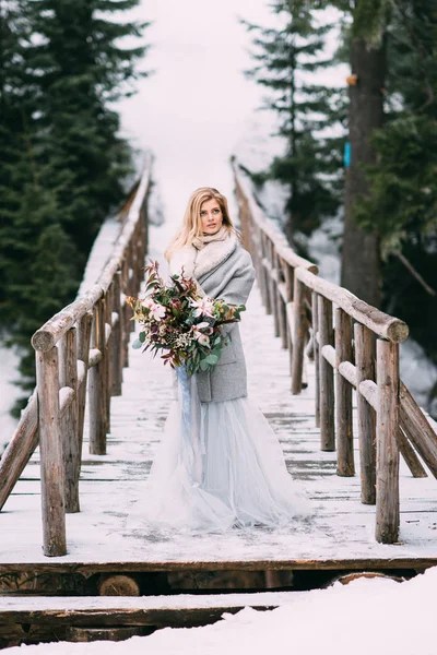 Piękna młoda dziewczyna stoi zimą z bukietem kwiatów w jej ręce — Zdjęcie stockowe