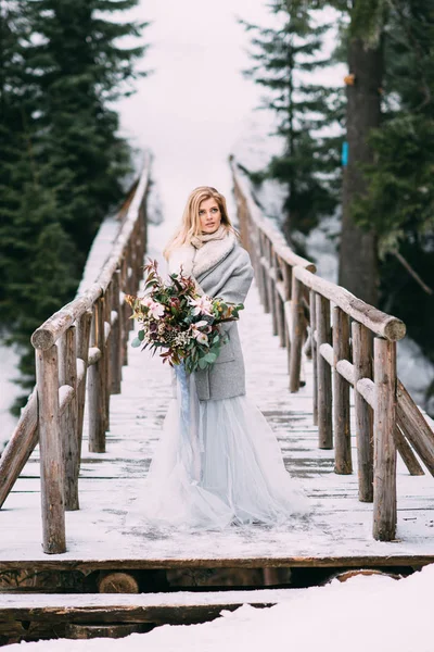 Mooi jong meisje staat in de winter met een boeket bloemen in haar handen — Stockfoto