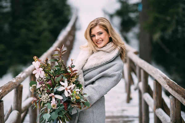 Mooi jong meisje staat in de winter met een boeket bloemen in haar handen — Stockfoto