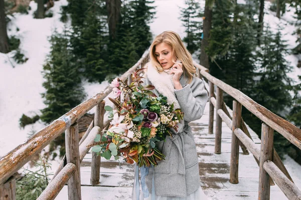 Güzel genç kız onun elinde bir buket çiçek ile kış duruyor — Stok fotoğraf
