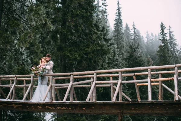 Mann umarmt Frau auf Holzbrücke in Berg — Stockfoto