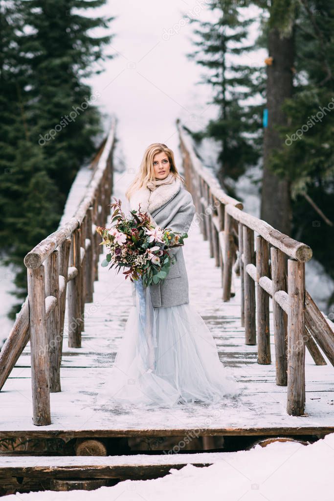 Beautiful young girl stands in winter with a bouquet of flowers in her hands