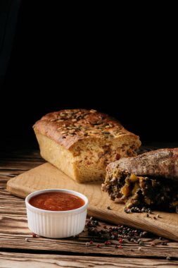 Kabak kek ve pişmiş et ile birlikte bir sos dolgulu ahşap plaka siyah bir arka plan üzerinde rulo