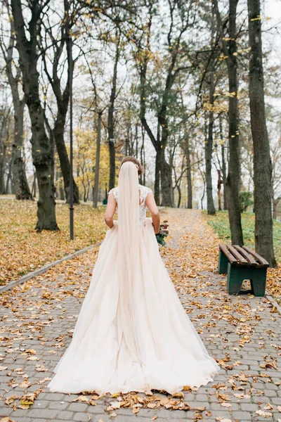 Hermosa novia con un ramo de boda en sus manos al aire libre en un parque — Foto de Stock