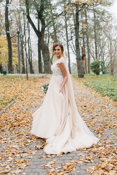 Bela noiva com um buquê de casamento em suas mãos ao ar livre em um parque — Fotografia de Stock