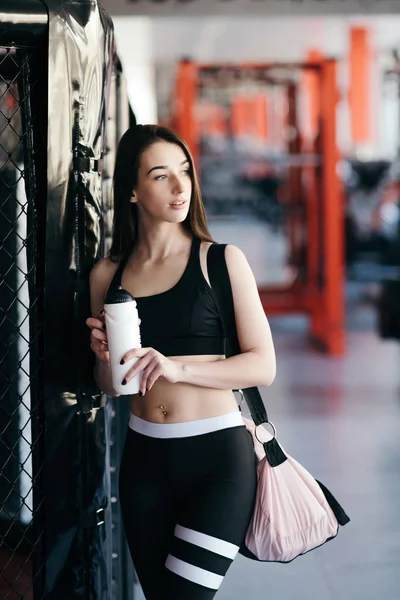 Beautiful young sportswoman in sportswear is holding a bottle of water — Stock Photo, Image
