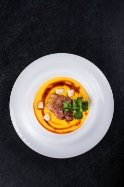 İştah açıcı bir balkabağı çorbası beyaz bir tabak bir restoranda servis edilir