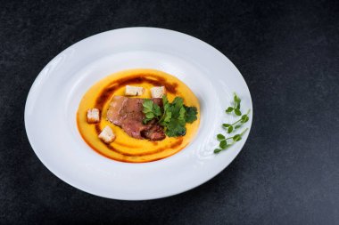 İştah açıcı bir balkabağı çorbası beyaz bir tabak bir restoranda servis edilir