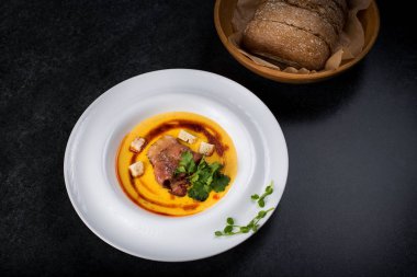 İştah açıcı bir balkabağı çorbası beyaz bir tabak bir restoranda servis edilir