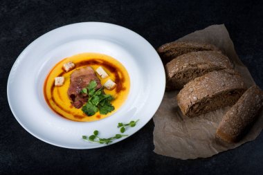 İştah açıcı bir balkabağı çorbası beyaz bir tabak bir restoranda servis edilir