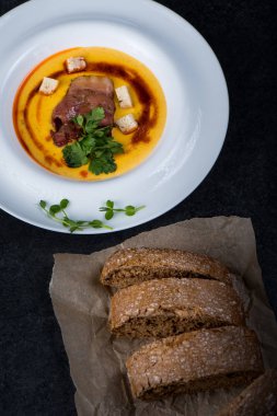 İştah açıcı bir balkabağı çorbası beyaz bir tabak bir restoranda servis edilir