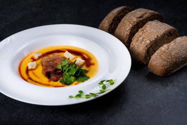 İştah açıcı bir balkabağı çorbası beyaz bir tabak bir restoranda servis edilir