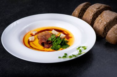 İştah açıcı bir balkabağı çorbası beyaz bir tabak bir restoranda servis edilir