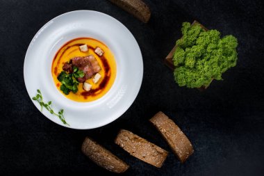 İştah açıcı bir balkabağı çorbası beyaz bir tabak bir restoranda servis edilir