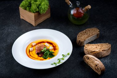 İştah açıcı bir balkabağı çorbası beyaz bir tabak bir restoranda servis edilir