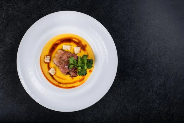 İştah açıcı bir balkabağı çorbası beyaz bir tabak bir restoranda servis edilir