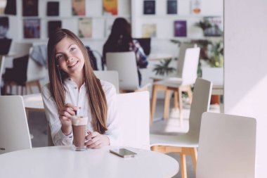 Güzel esmer yaz terasında kahve içme. Bir genç kız ile bir smartphone onun elinde bir kafede zaman harcıyor