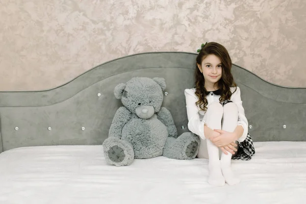 Το χαριτωμένο μικρό κορίτσι να κάθεται σε μια κρεβατοκάμαρα για ένα μεγάλο κρεβάτι — Φωτογραφία Αρχείου