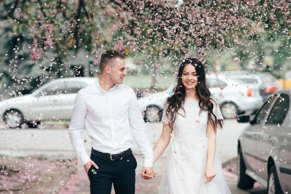 Feliz jovem casal apaixonado goza de dia de primavera, homem amoroso segurando as mãos sua mulher despreocupada andando no parque — Fotografia de Stock