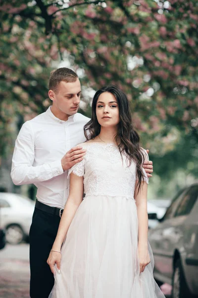 Feliz joven pareja enamorada disfruta del día de primavera, hombre amoroso sosteniendo en las manos a su mujer sin preocupaciones caminando por el parque — Foto de Stock