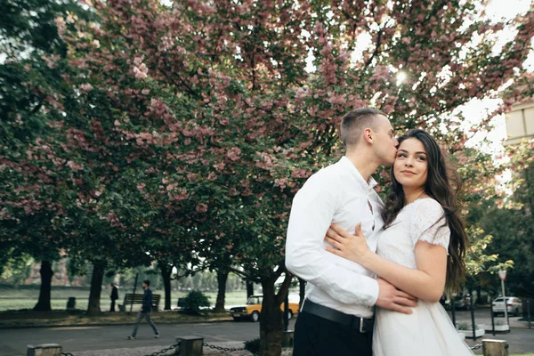 Счастливая молодая пара влюблена наслаждается весенним днем, любящий мужчина держит на руках свою женщину беззаботной прогулки в парке — стоковое фото