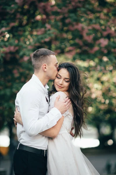 Feliz jovem casal apaixonado goza de dia de primavera, homem amoroso segurando as mãos sua mulher despreocupada andando no parque — Fotografia de Stock