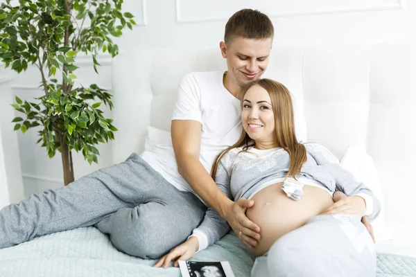 Young couple - man and woman expecting baby, looking at baby clo — Stock Photo, Image