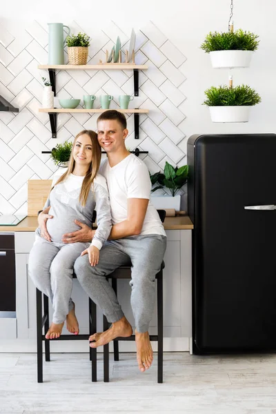 Young couple - man and woman expecting a baby, spend time in the kitchen. Awaiting the birth of a baby — Stock Photo, Image