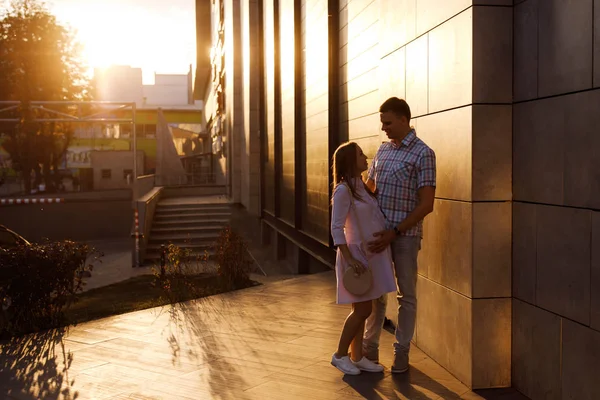 Casal jovem - homem e mulher esperando um bebê, passar o tempo juntos na rua da cidade ao pôr do sol . — Fotografia de Stock