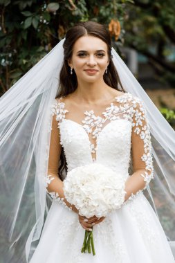 Parkta ellerinde düğün buketi olan güzel bir gelin. Düğün günü.