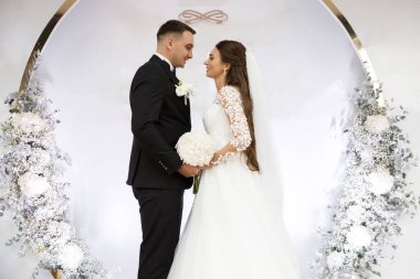 Bir çift gelin düğün günlerinde düğün kemerinin yanında duruyor..