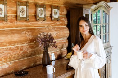 Güzel kız, mutfakta, tahta bir evde kahve hazırlıyor..