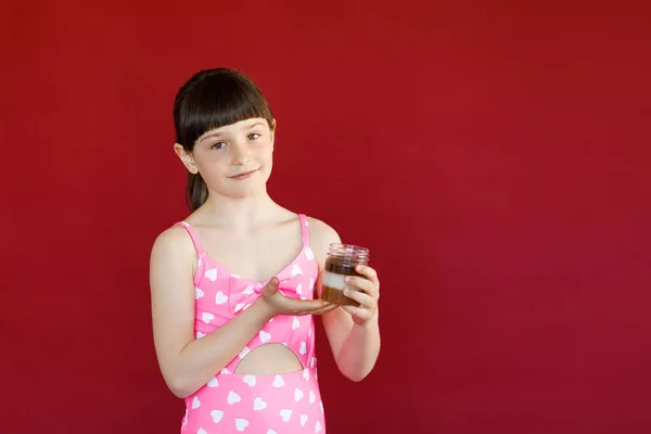 Isolado tiro de encantadora menina em maiô posando em estúdio com segurando cupcake na mão . — Fotografia de Stock