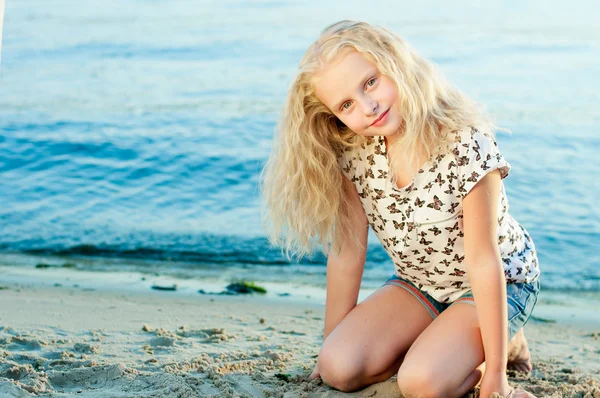 Menina na areia perto da água — Fotografia de Stock