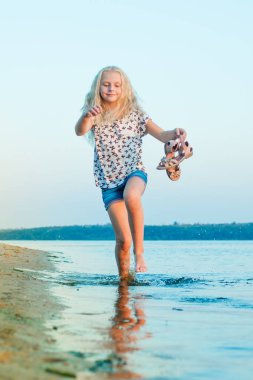 plajda çıplak ayakla su üzerinde çalışan kız