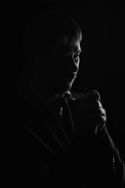 Man low key high-contrast profile portrait in backlight with a serious look on his face clipart
