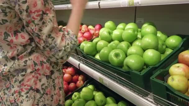 Беременная женщина выбирает и нюхает зеленые яблоки в продуктовом магазине — стоковое видео