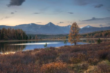 Dağ silsilesi hafif pembe gökyüzü zemin üzerine, ayna yüzey Gölü sonbahar yatay