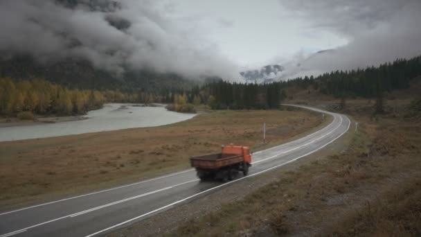 Camion che viaggiano su una strada tortuosa lungo il fiume in una nuvolosa giornata di pioggia autunnale, Siberia, Altai — Video Stock
