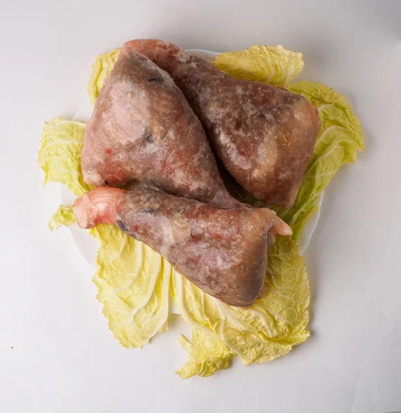 Patas de pollo crudas en plato con lechuga. Aislado — Foto de Stock