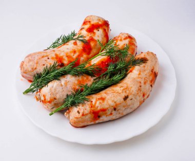 Beyaz plaka üzerinde çiğ sosis. İzole