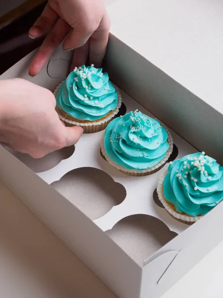 Menina coloca cupcakes na caixa de papel — Fotografia de Stock