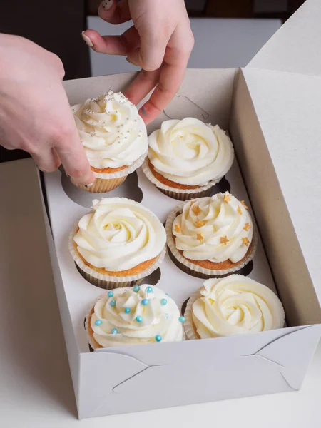 Menina coloca cupcakes na caixa de papel — Fotografia de Stock